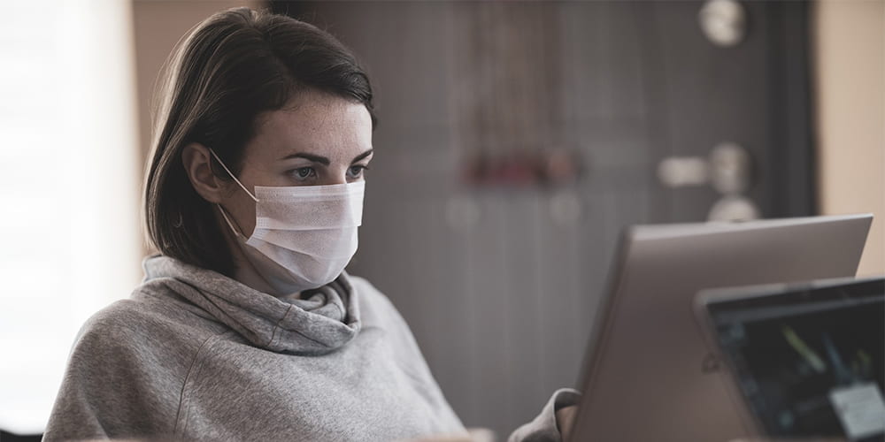 woman wearing mask working at computer